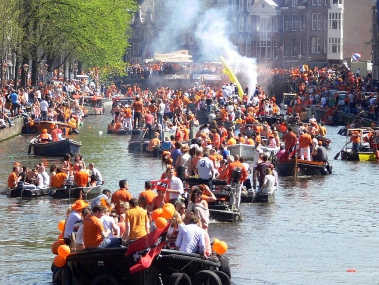 Bootje huren Koningsdag Amsterdam - Grachten met feestende mensen