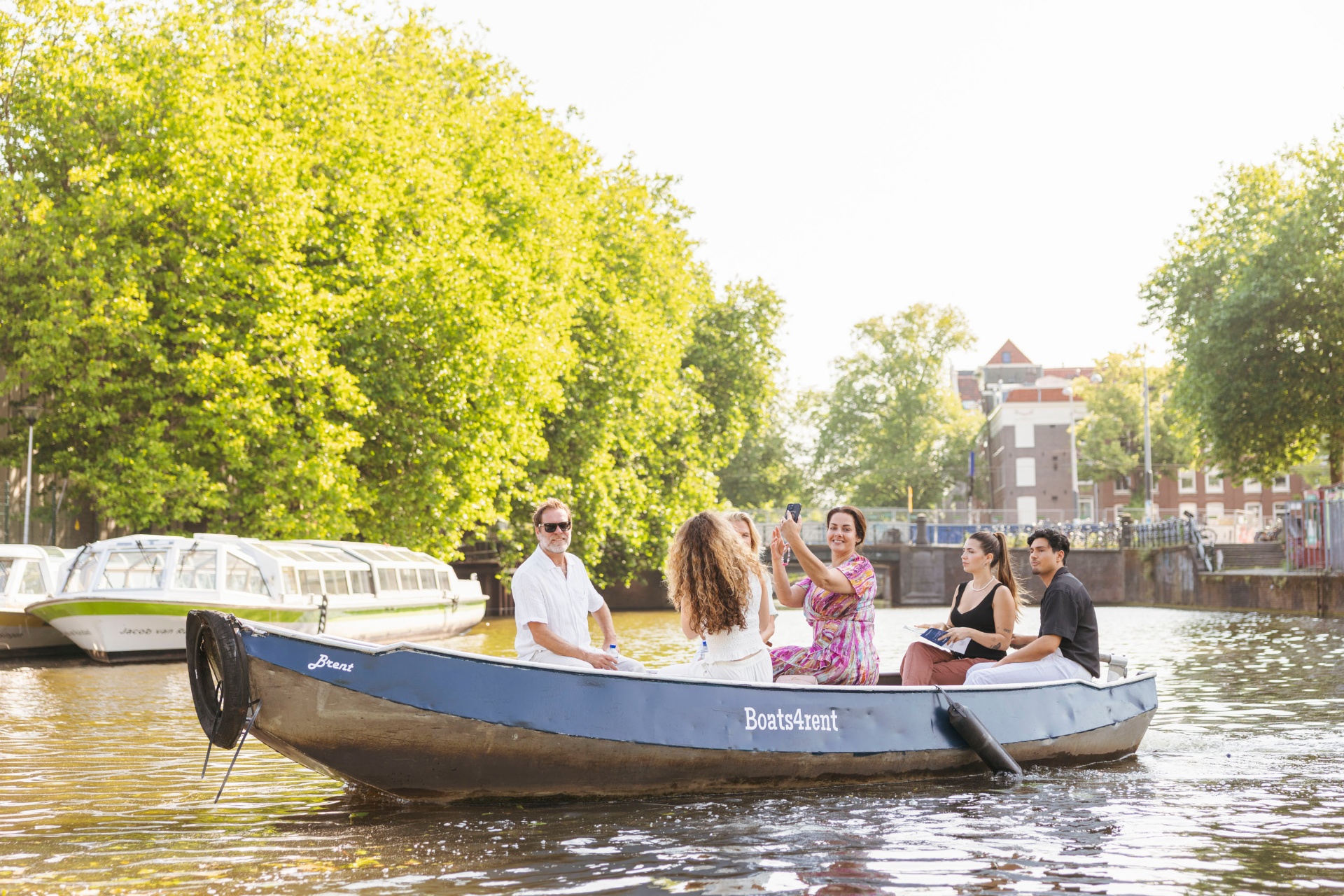 Groep vaart in elektrische sloep langs Amsterdamse windmolen