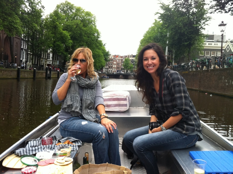 Twee vrouwen met hapjes en drankjes op een sloep op de Amsterdamse grachten.