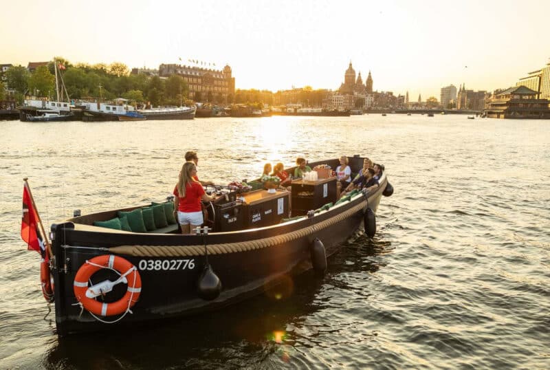 Open boat with skipper during sunset on the Amsterdam canals.