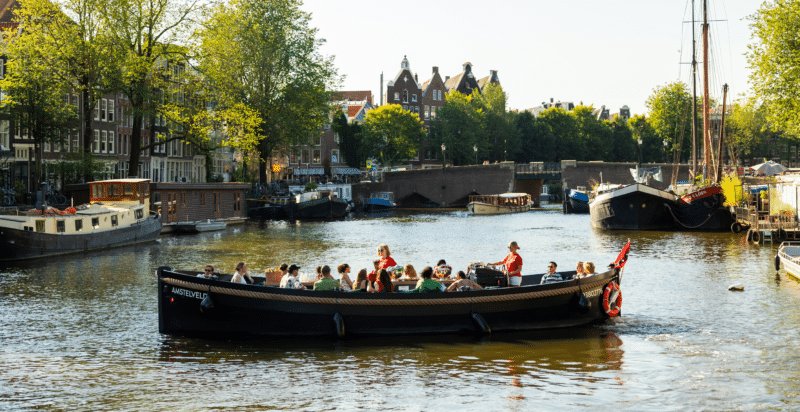 A group of people on a private open boat tour through the Amsterdam canals.